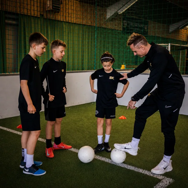 Stefan Kehrer zeigt drei Kindern eine Technikübung mit dem Ball in der Soccerhalle